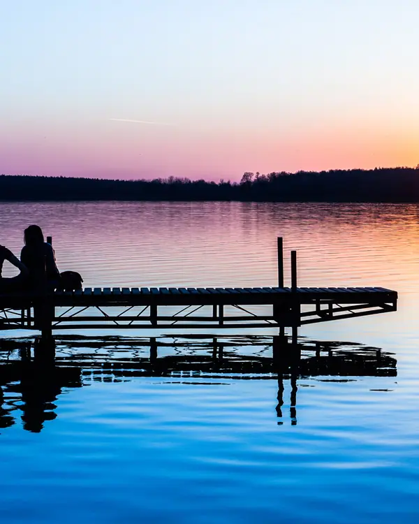 Casal em um deck olhando o pôr do sol sobre a água