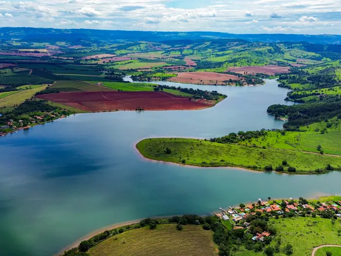 Represa entre campos verdes, em dia de céu aberto